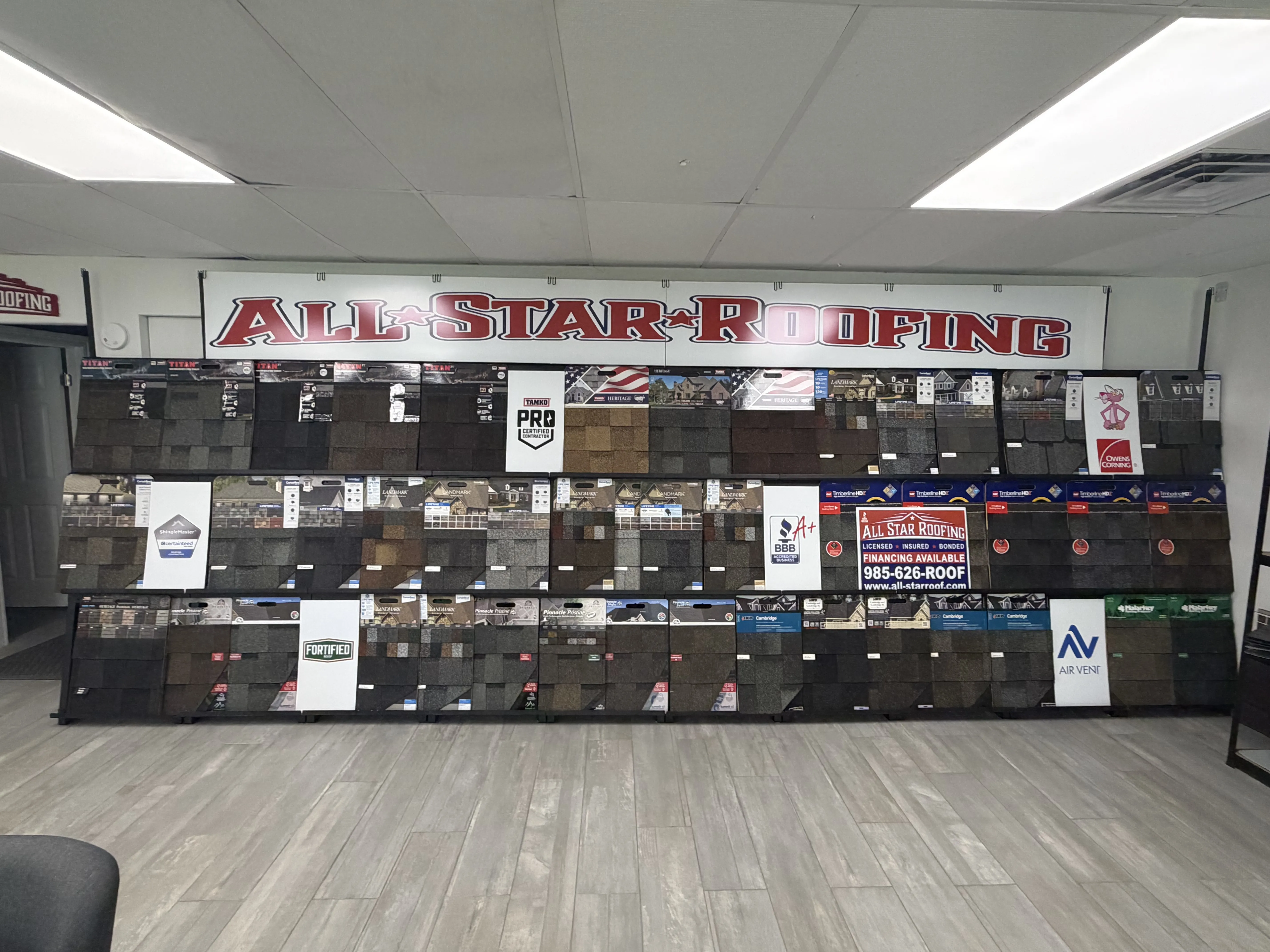All Star Roofing shingle display wall with TAMKO, Owens Corning, CertainTeed samples